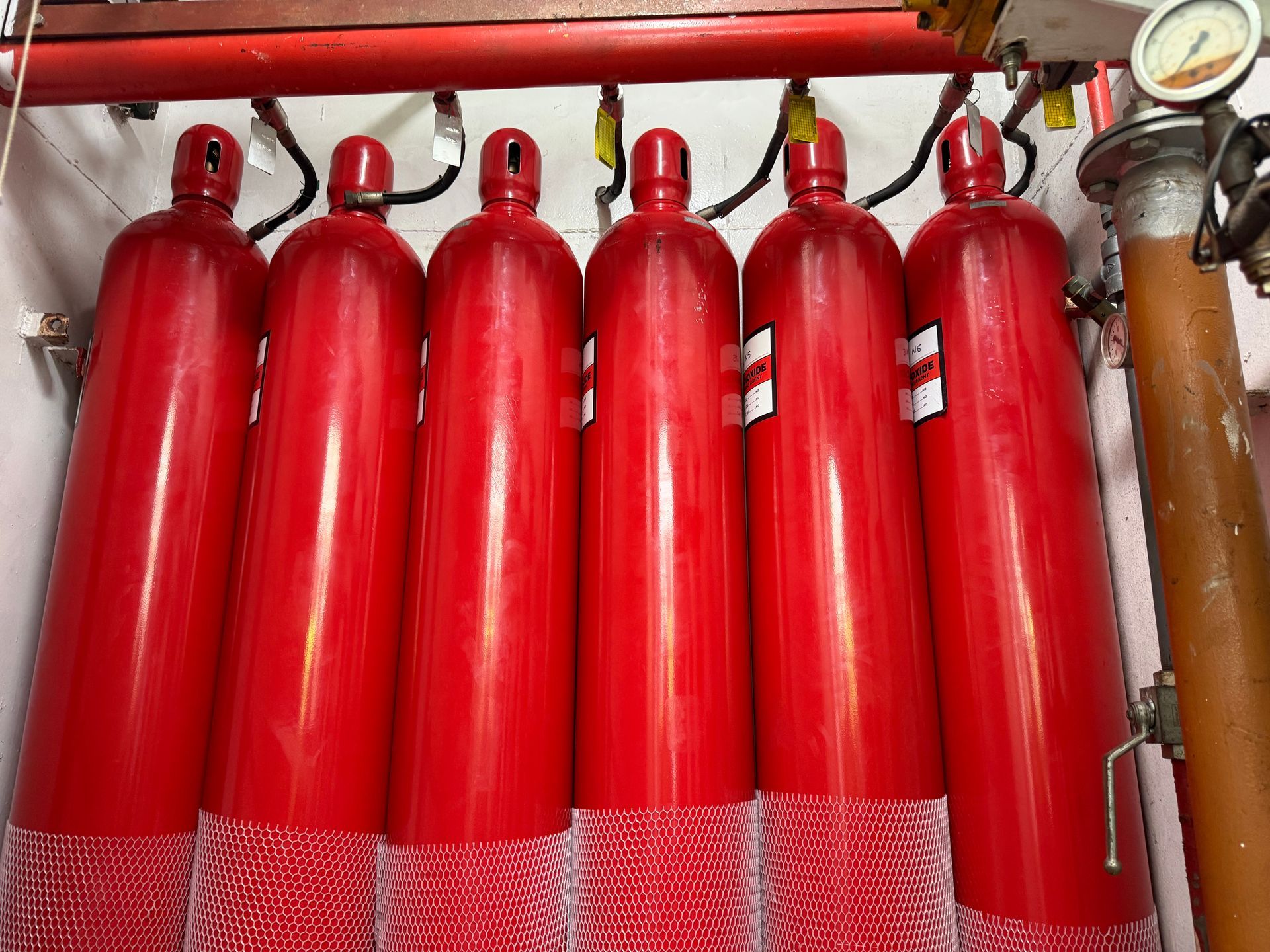 Row Of Red Fire Suppression Cylinders With Pressure Gauge in an Industrial Setting — Flaming North Fire Protection Pty Ltd in Garbutt, QLD