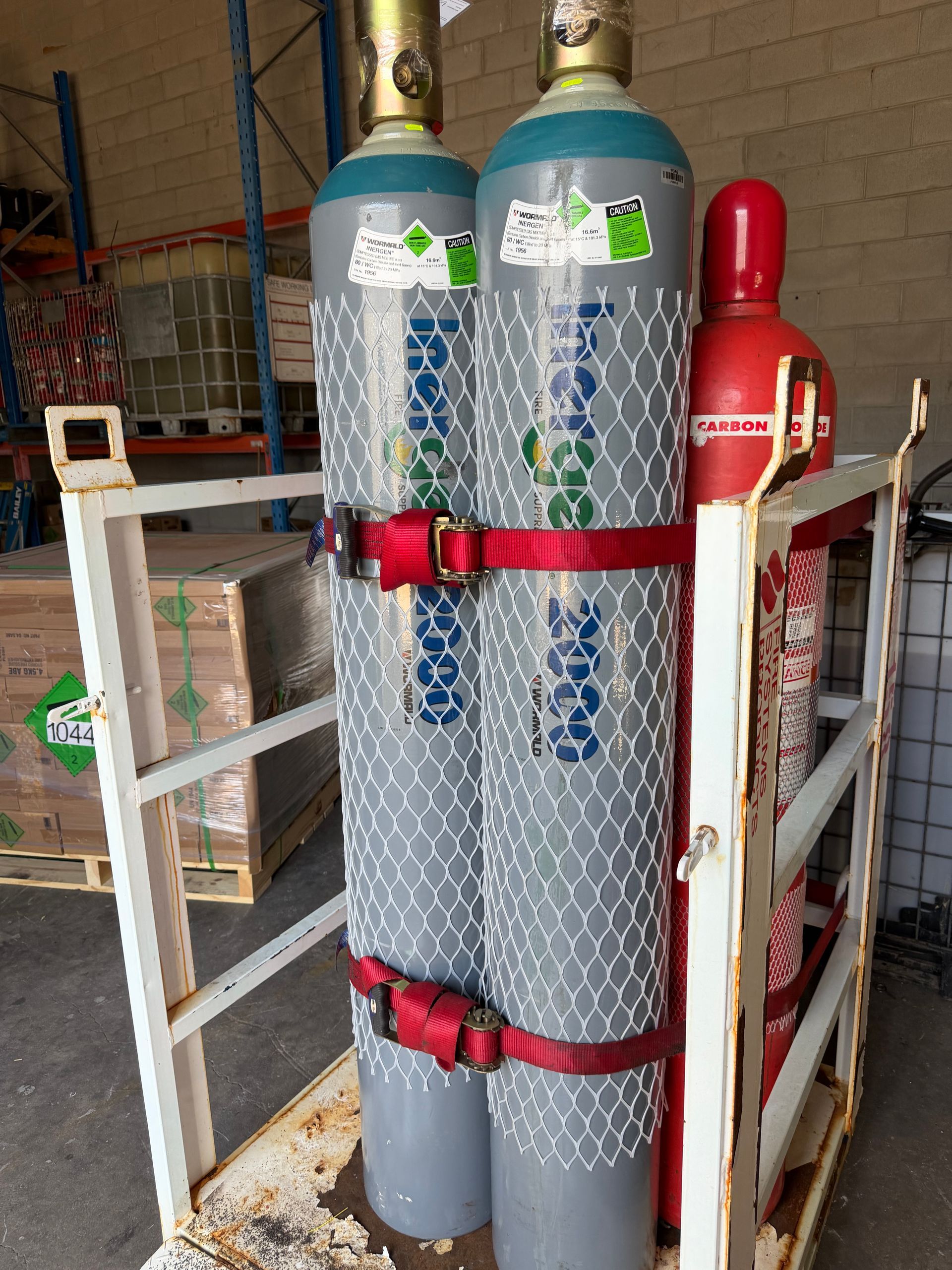 Two Gas Cylinders Secured in a Metal Cart, One Grey and One Red, Inside a Storage Area — Flaming North Fire Protection Pty Ltd in Garbutt, QLD