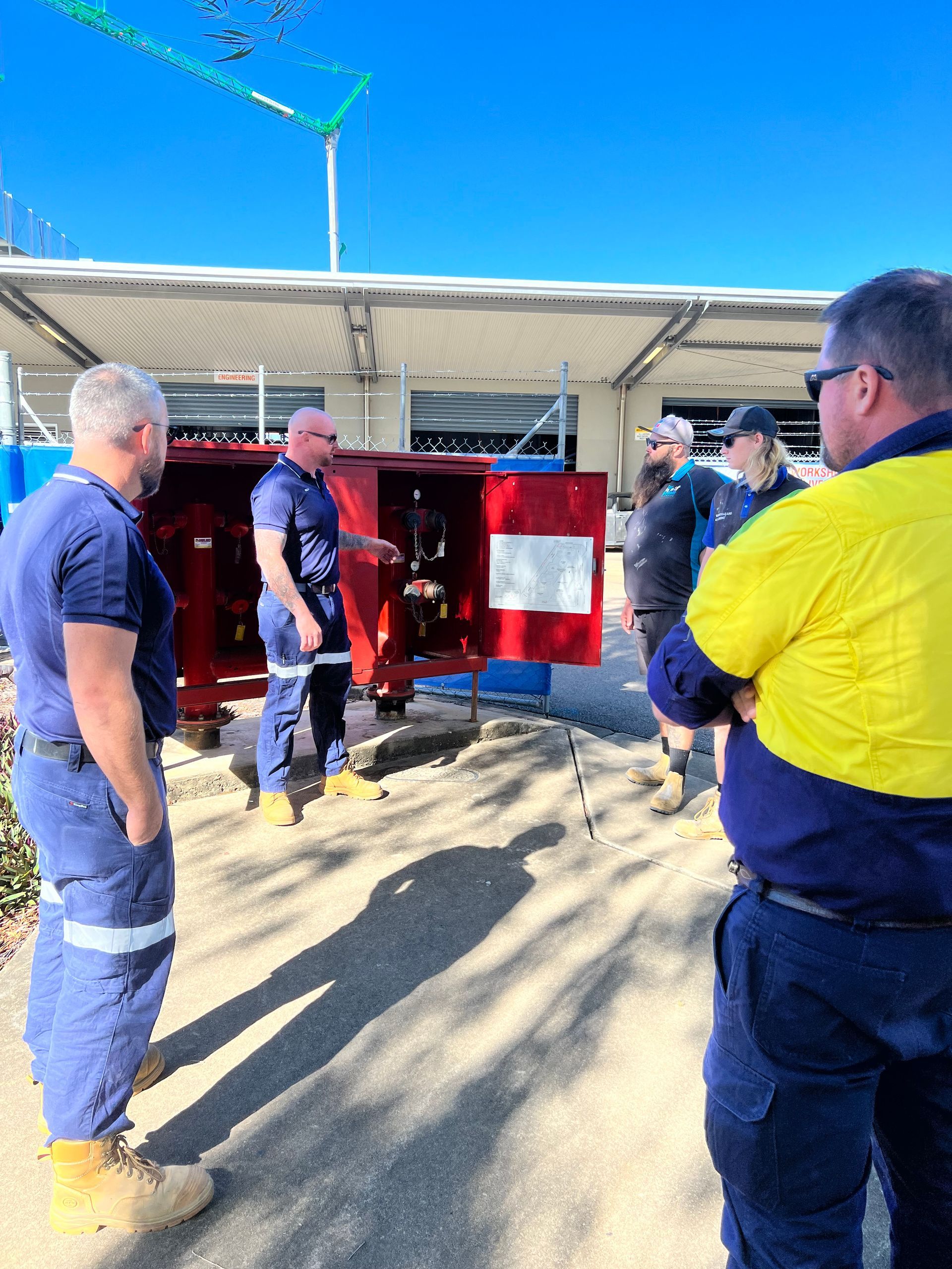 Workers Gather Around a Red Fire Truck in a Bright Outdoor Garage Area. — Flaming North Fire Protection Pty Ltd in Garbutt, QLD