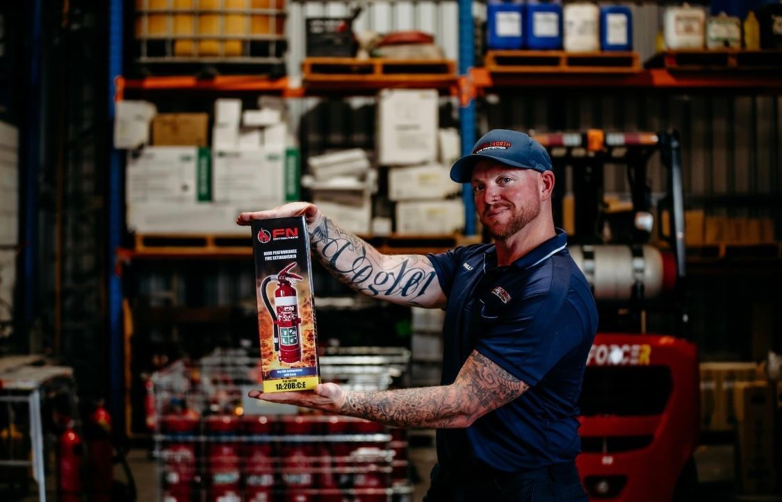 Worker In a Warehouse Holding a Boxed Product, With Shelves and Stacked Inventory in the Background — Flaming North Fire Protection Pty Ltd in Charters Towers, QLD