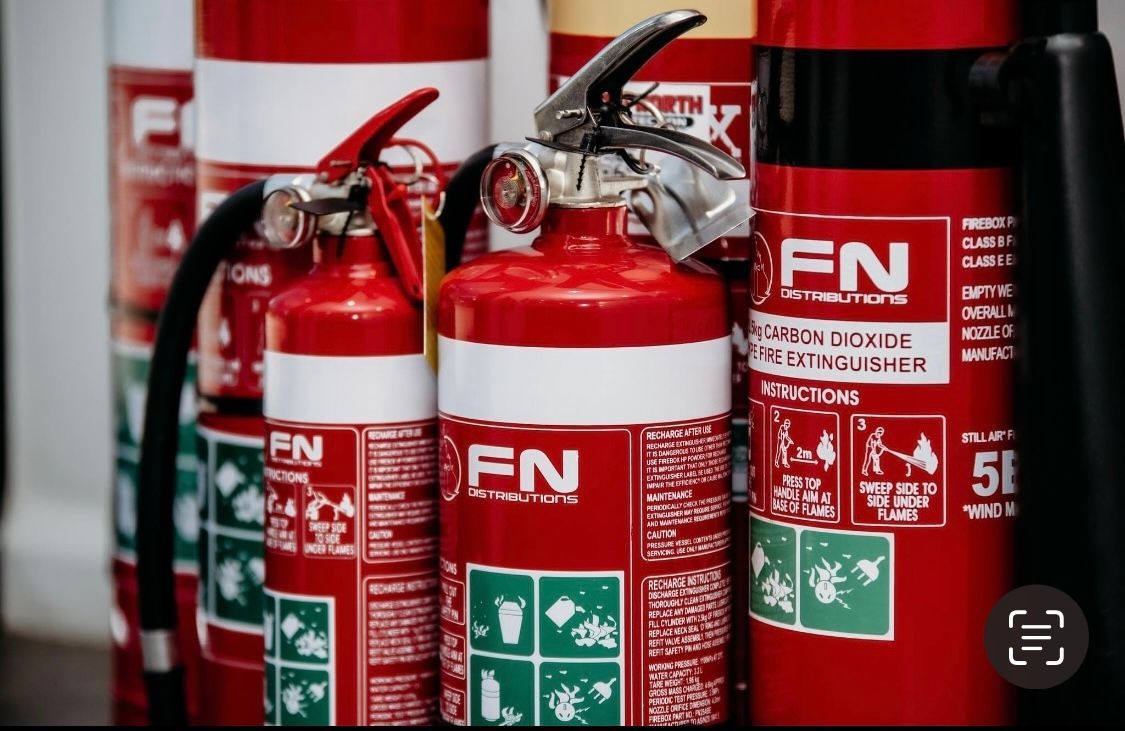 Red Fire Extinguishers Lined Up Indoors, With Red and Green Labels Visible — Flaming North Fire Protection Pty Ltd in Garbutt, QLD
