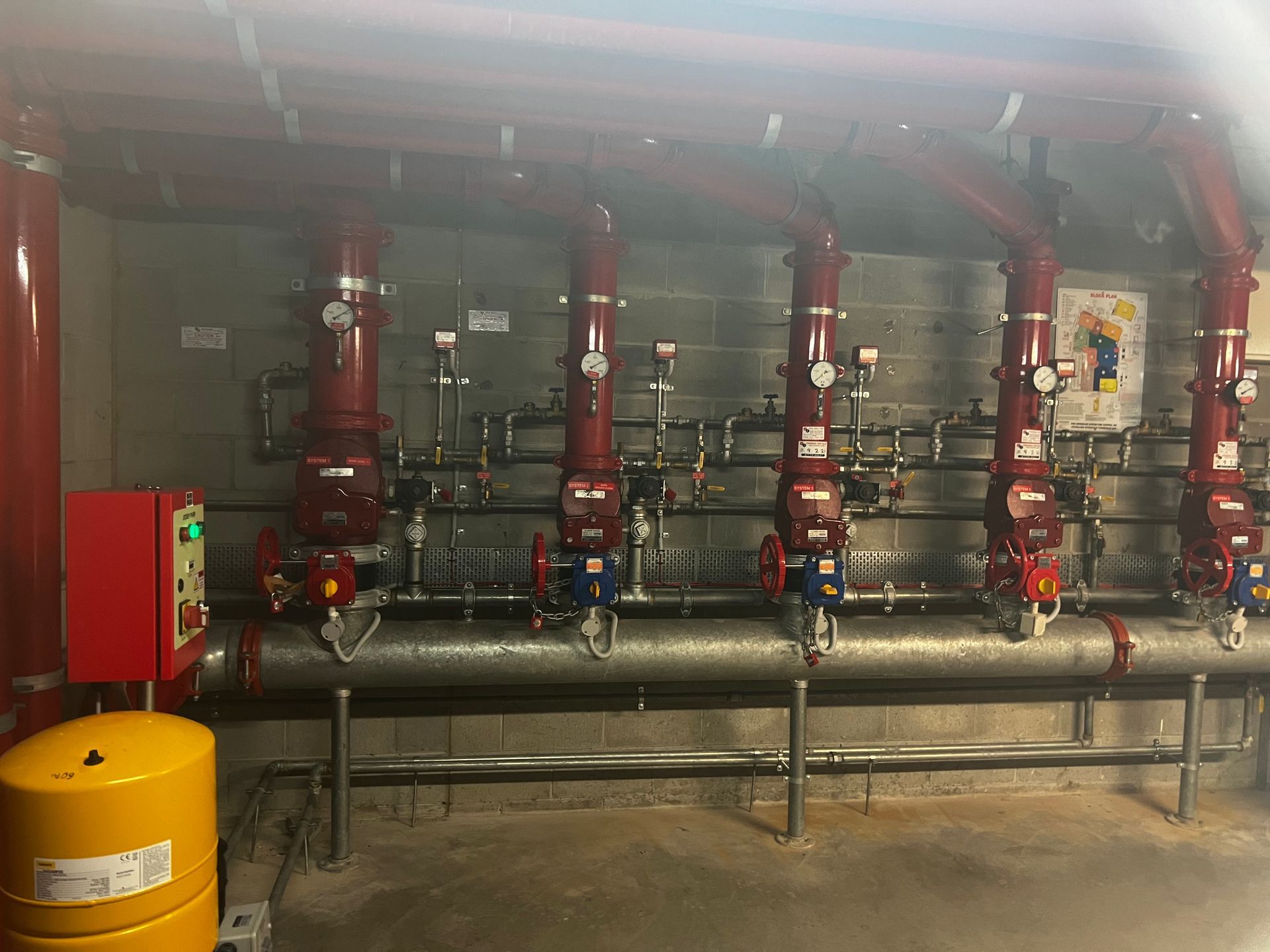 Industrial Mechanical Room With Red Pipes, Valves, and Large Grey Ducts Along a Concrete Wall — Flaming North Fire Protection Pty Ltd in Garbutt, QLD