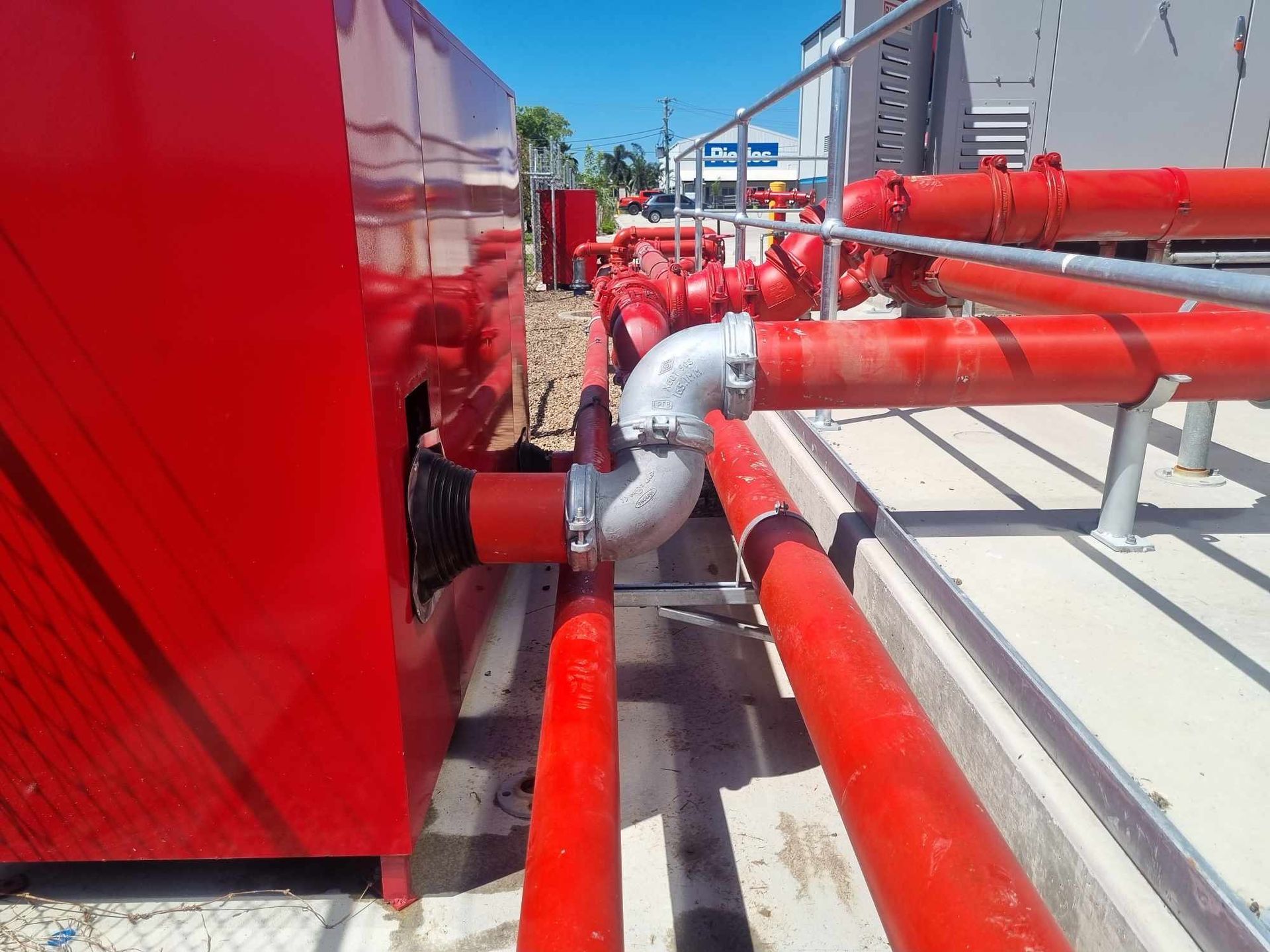 Red Industrial Pipes and Valves on a Rooftop Beside a Large Red Unit Under a Blue Sky — Flaming North Fire Protection Pty Ltd in Garbutt, QLD