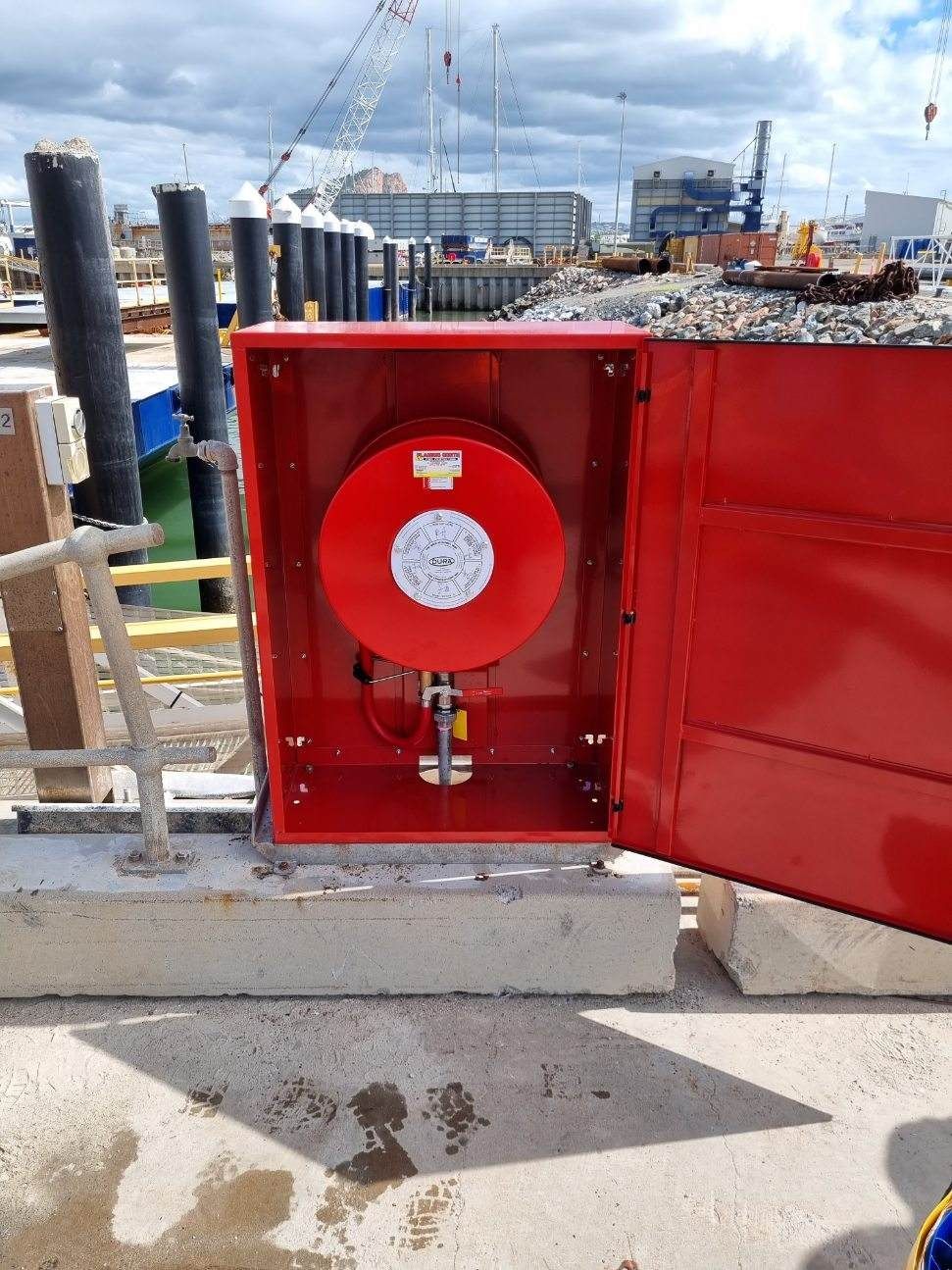 Red Fire Hose Reel in an Open Red Cabinet on a Construction Site by the Waterfront — Flaming North Fire Protection Pty Ltd in Garbutt, QLD