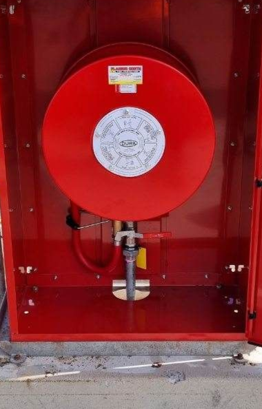 Red Fire Hose Reel Inside a Wall Cabinet With a Nozzle and Hose Visible — Flaming North Fire Protection Pty Ltd in Garbutt, QLD