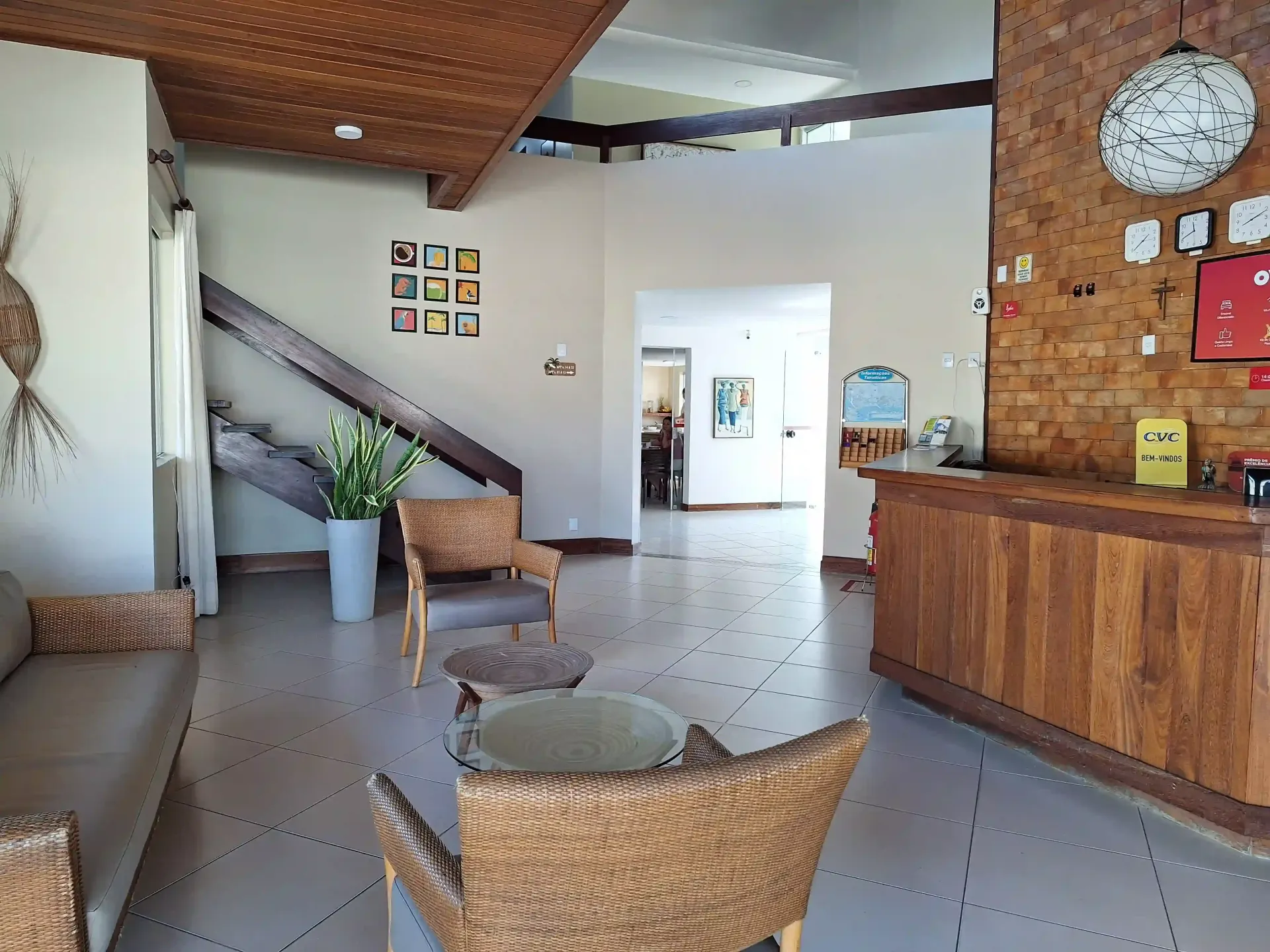 Uma sala de estar com sofá, mesa, cadeiras e escadas- Alto da Praia Hotel