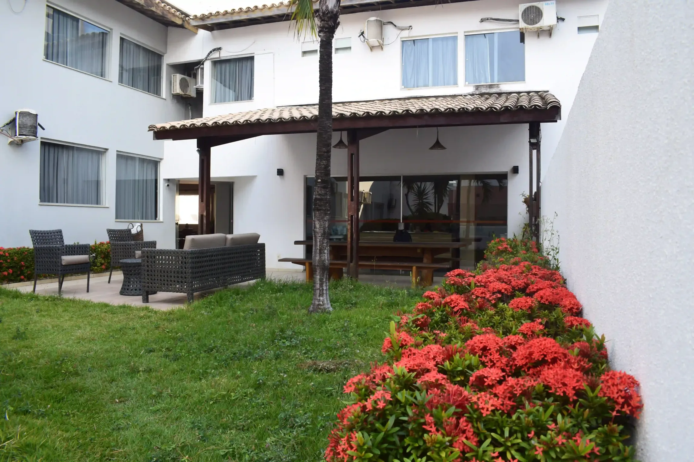 Uma casa branca com um pátio e flores na frente - Alto da Praia Hotel