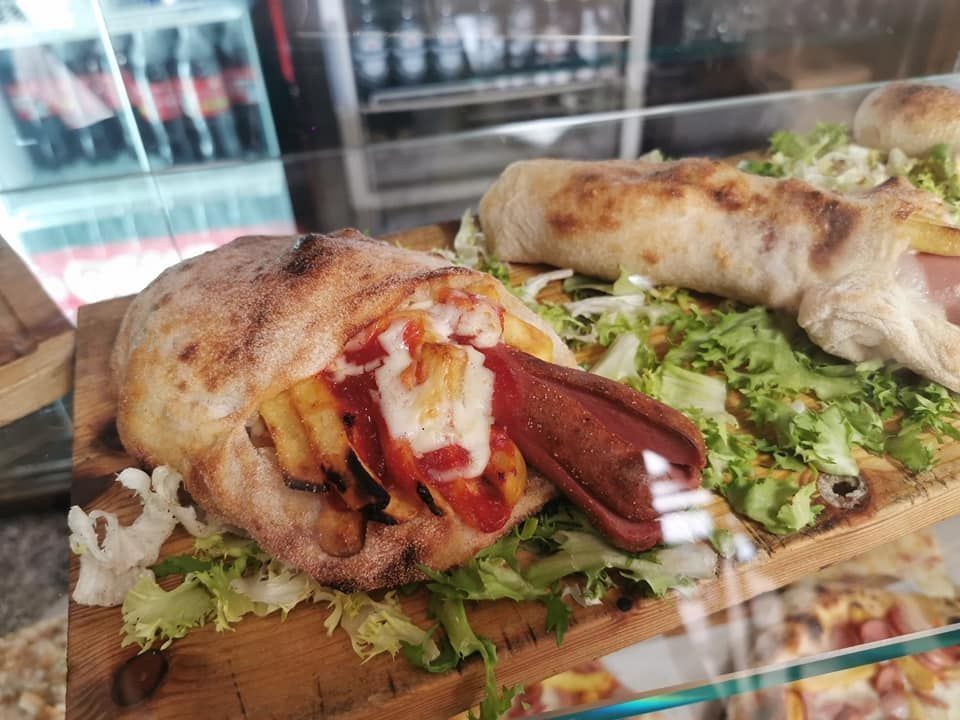 Maiale intero arrosto su un vassoio di legno con guarnizione di lattuga e pane sullo sfondo.