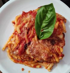 Piatto di pasta al sugo di pomodoro con guarnizione di foglie di basilico.