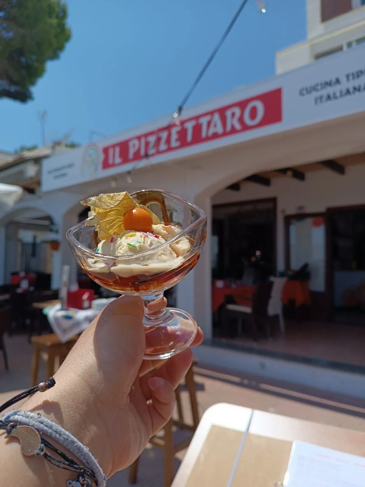 Hand holding a dessert cup outside Il Pizzettaro pizzeria on a sunny day