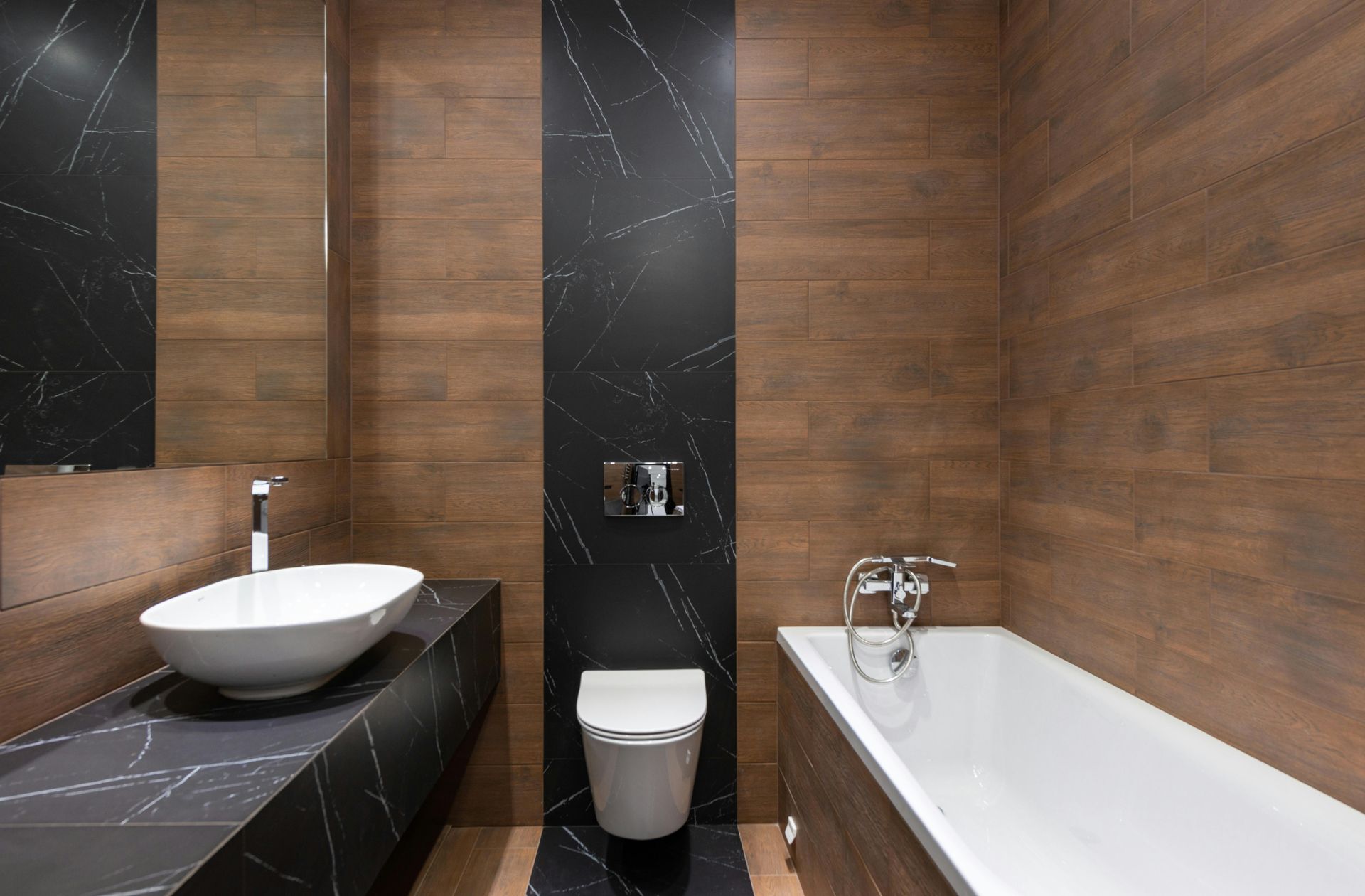 Modern bathroom with wooden and black tile walls, white sink, toilet, and bathtub.