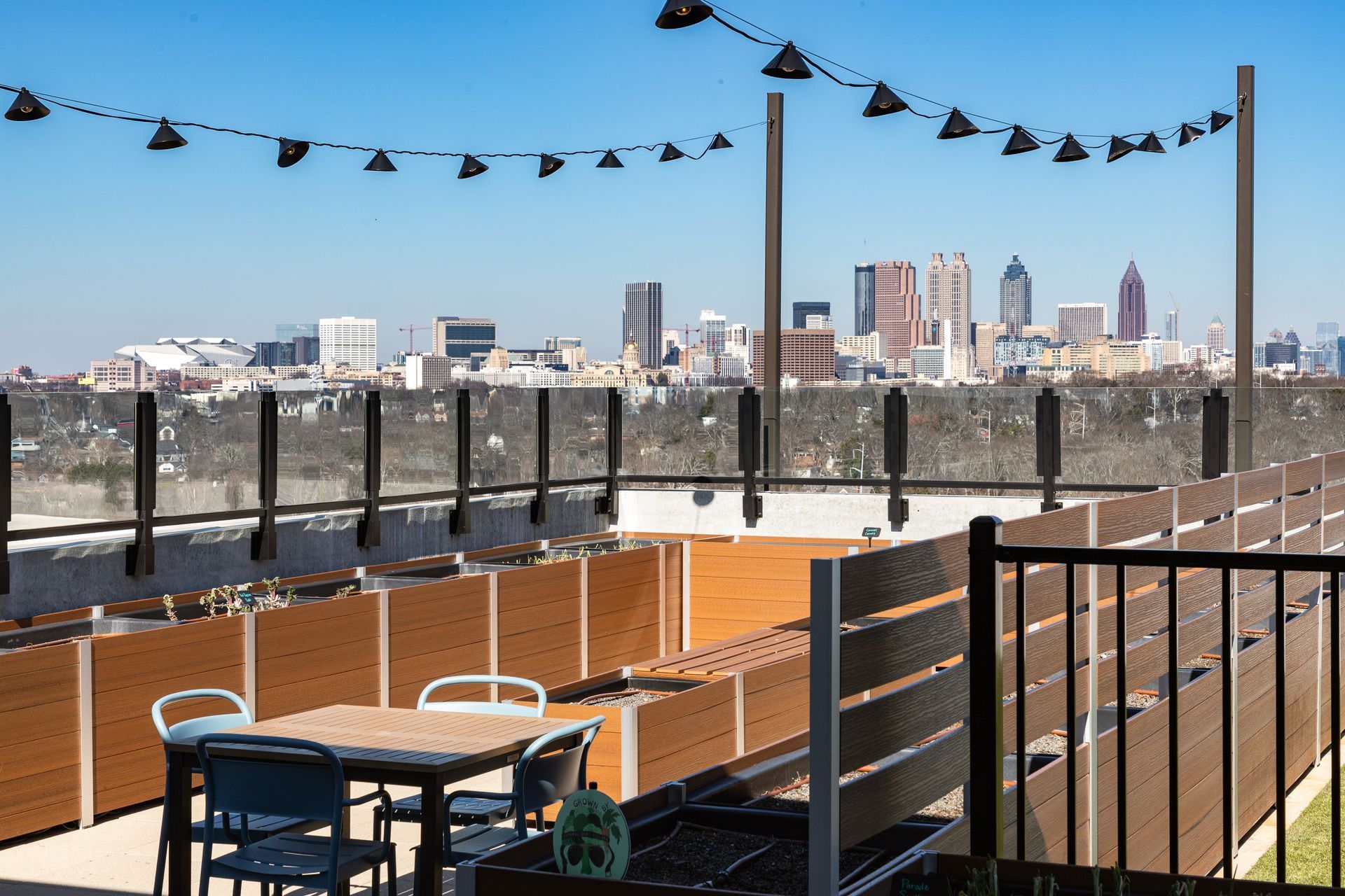 A rooftop patio with a dining table and chairs, featuring a clear view of the Atlanta city skyline.