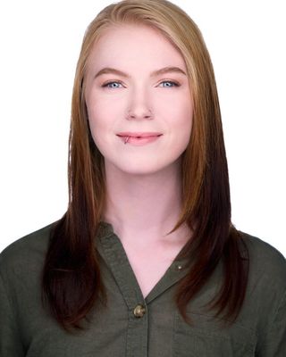 Studio headshot of a smiling woman with blonde hair wearing a dark green blouse on a white background
