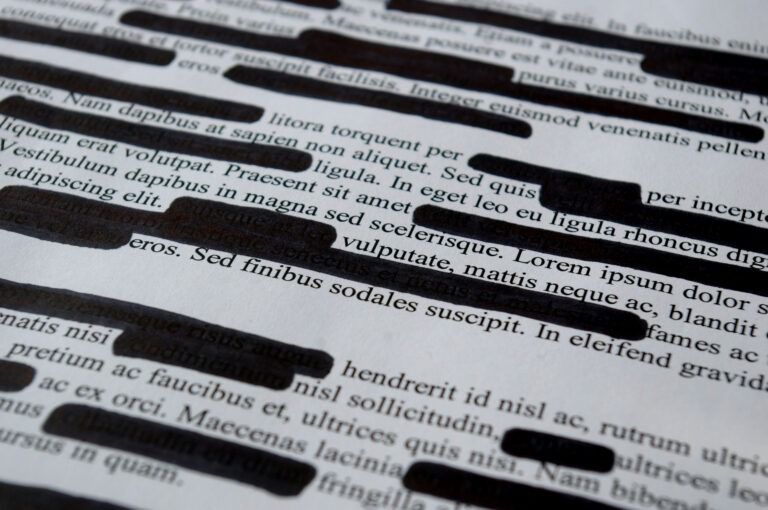 Close-up of a page with black ink scribbles and highlighted text on printed Latin text.