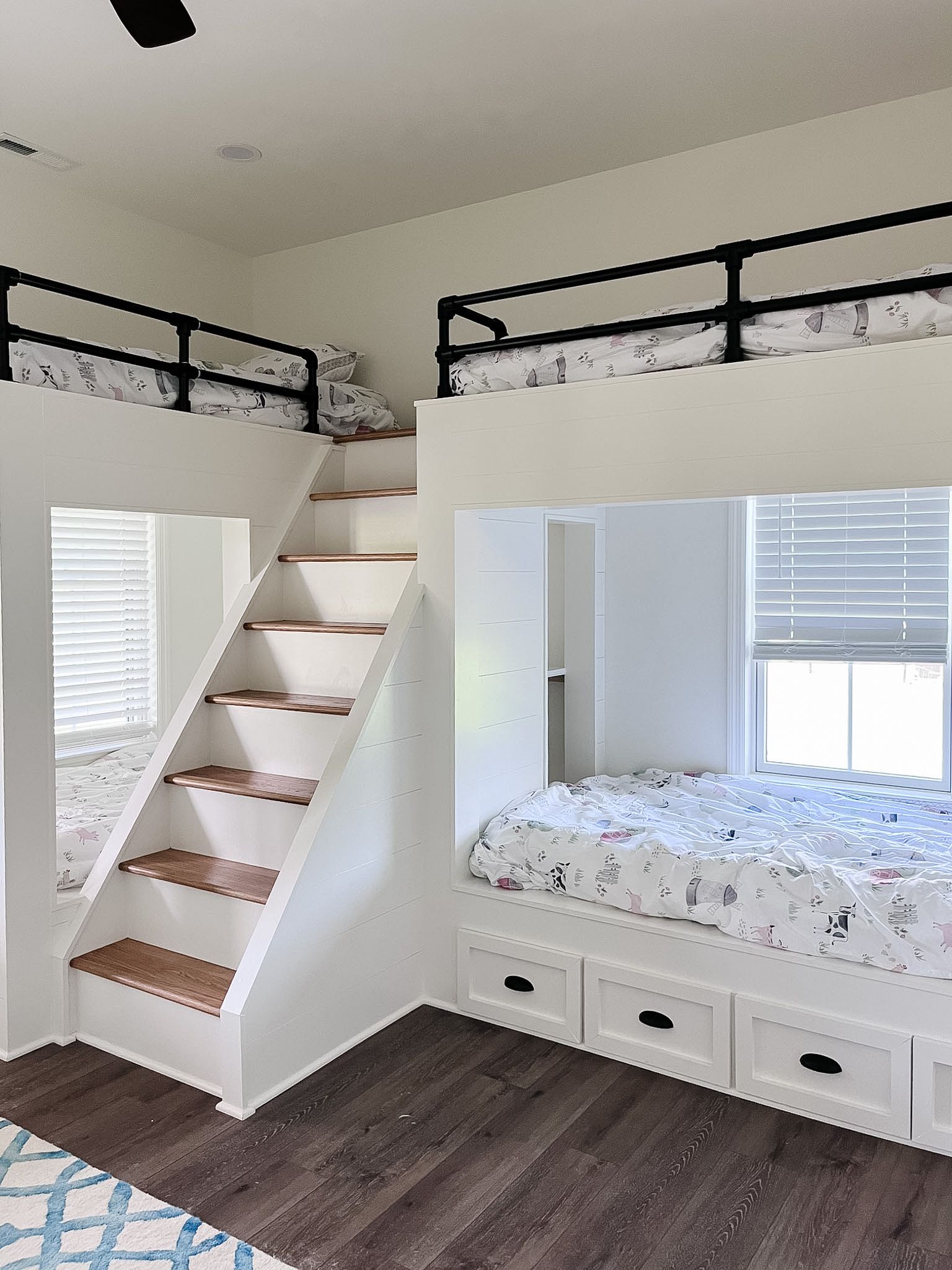 Loft bedroom with staircase to bunk bed, white furniture, dark wood floor, and window bench seat