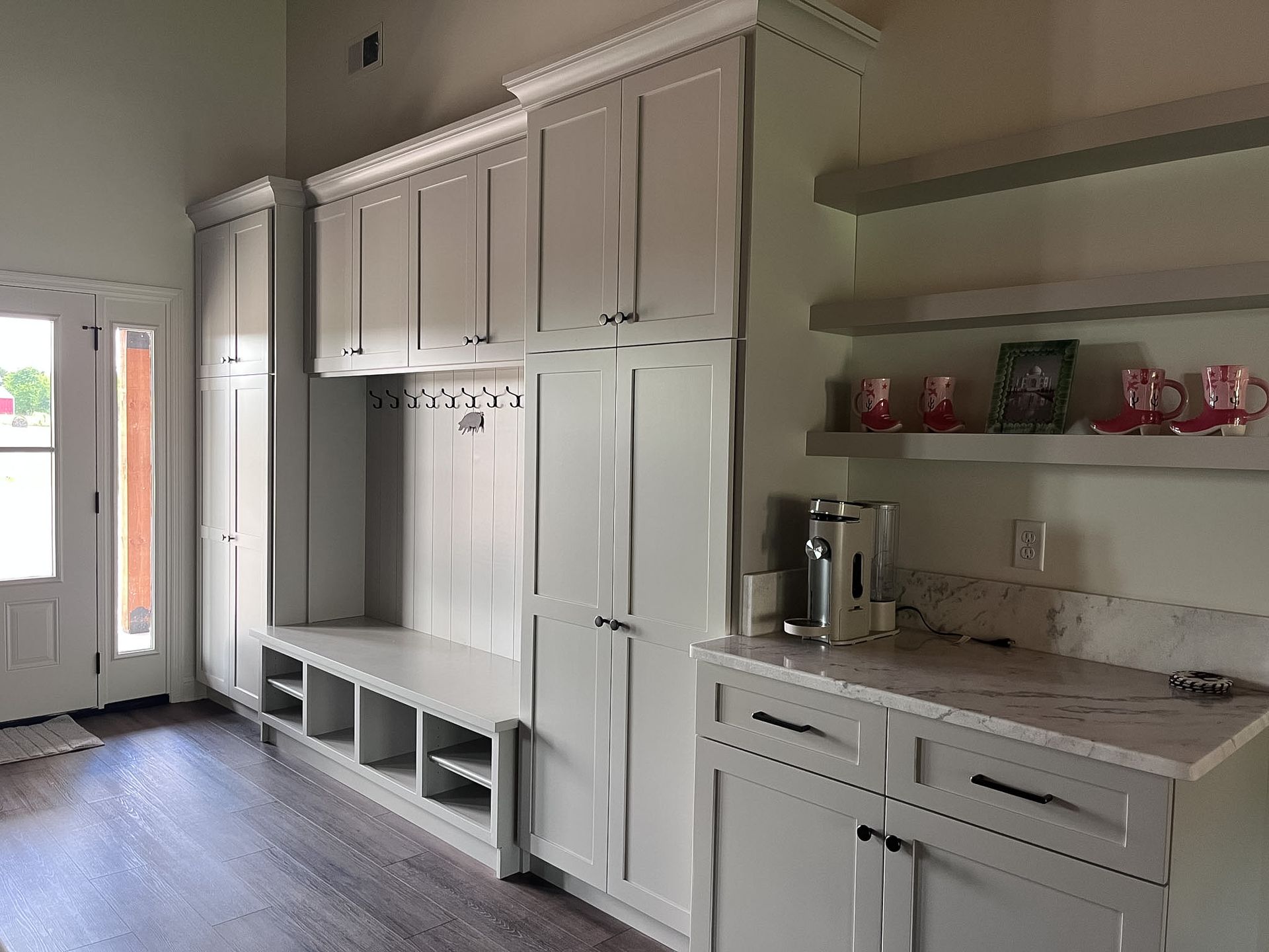 Bright kitchen with white cabinets, built-in benches, granite countertops, and a door to the outside.