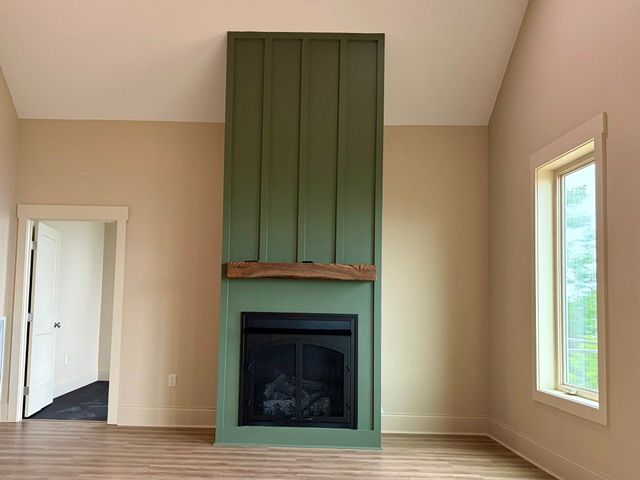 Empty beige living room with green fireplace wall and tall windows on both sides