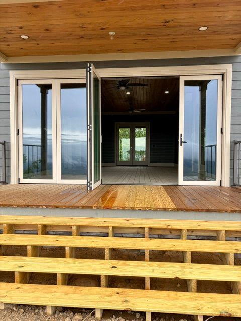 Wooden deck with open double doors leading into a dim interior, framed by a timber ceiling and white trim.