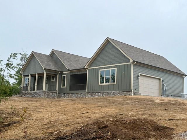Gray house with white garage on a bare dirt lot under construction