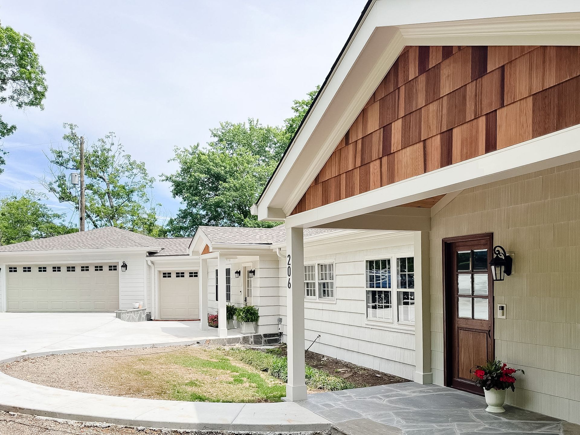 Modern suburban home exterior with garage, covered porch, and white siding with brown shingle accents