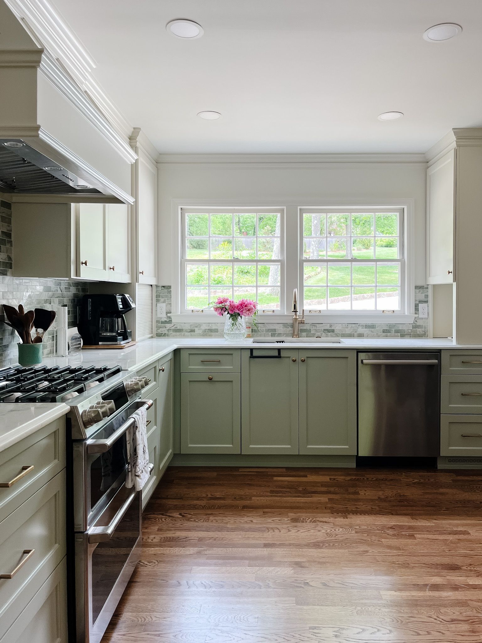 Bright kitchen with white cabinets, green lower cabinets, stainless appliances, and a window over the sink.