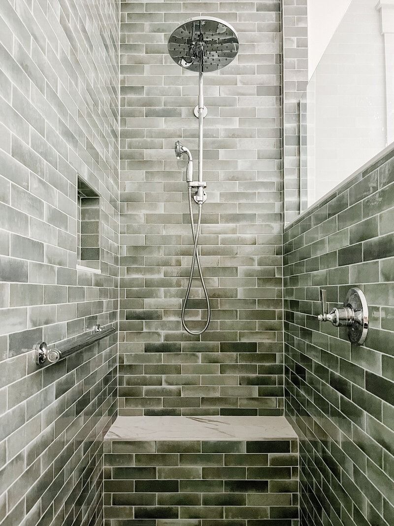 Tiled walk-in shower with overhead rain showerhead, handheld shower, built-in bench, and grab bars.