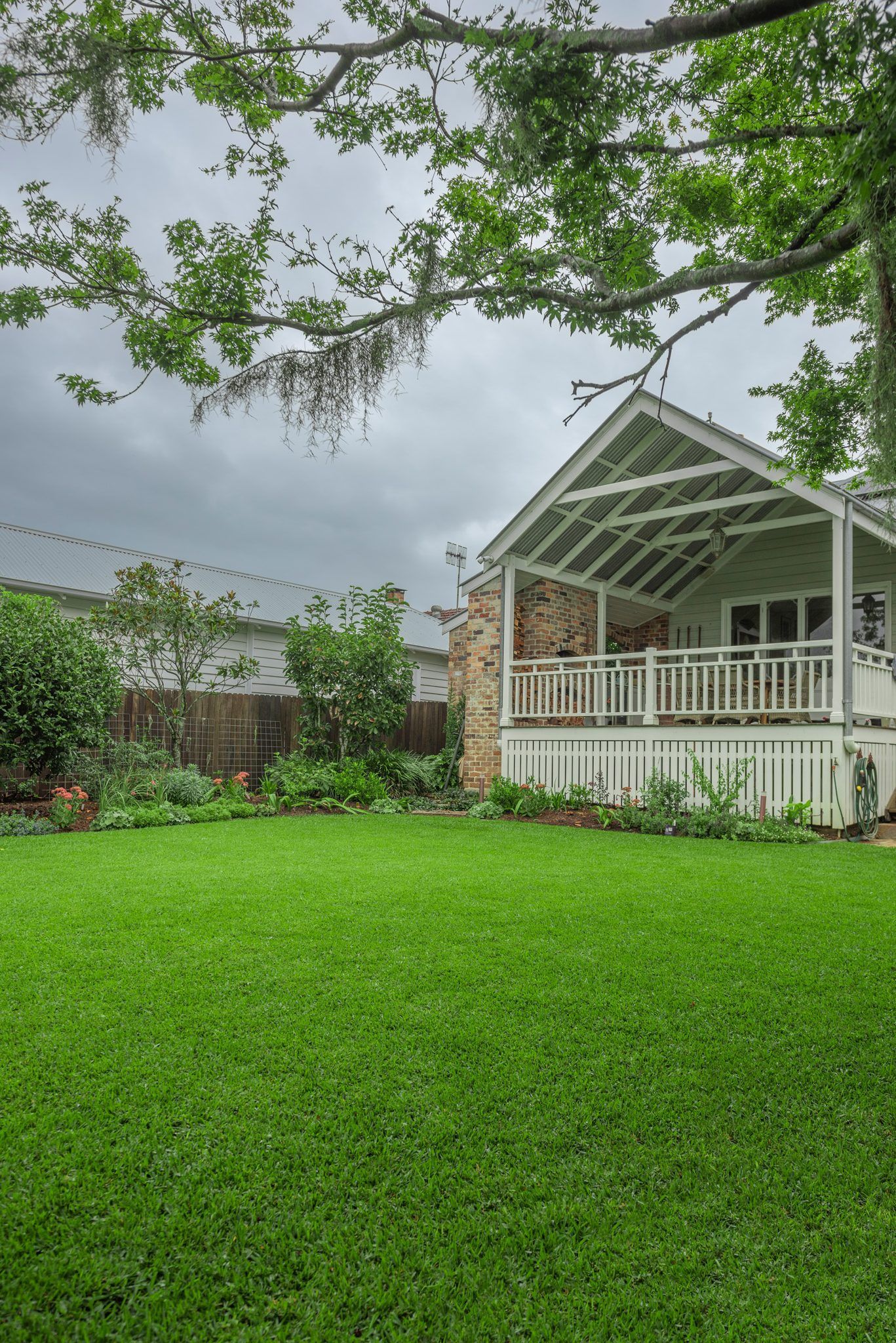 Lush Green Backyard with A White Porch and Overhanging Tree Branches — Tweed Landscape Supplies in Tweed Heads, NSW