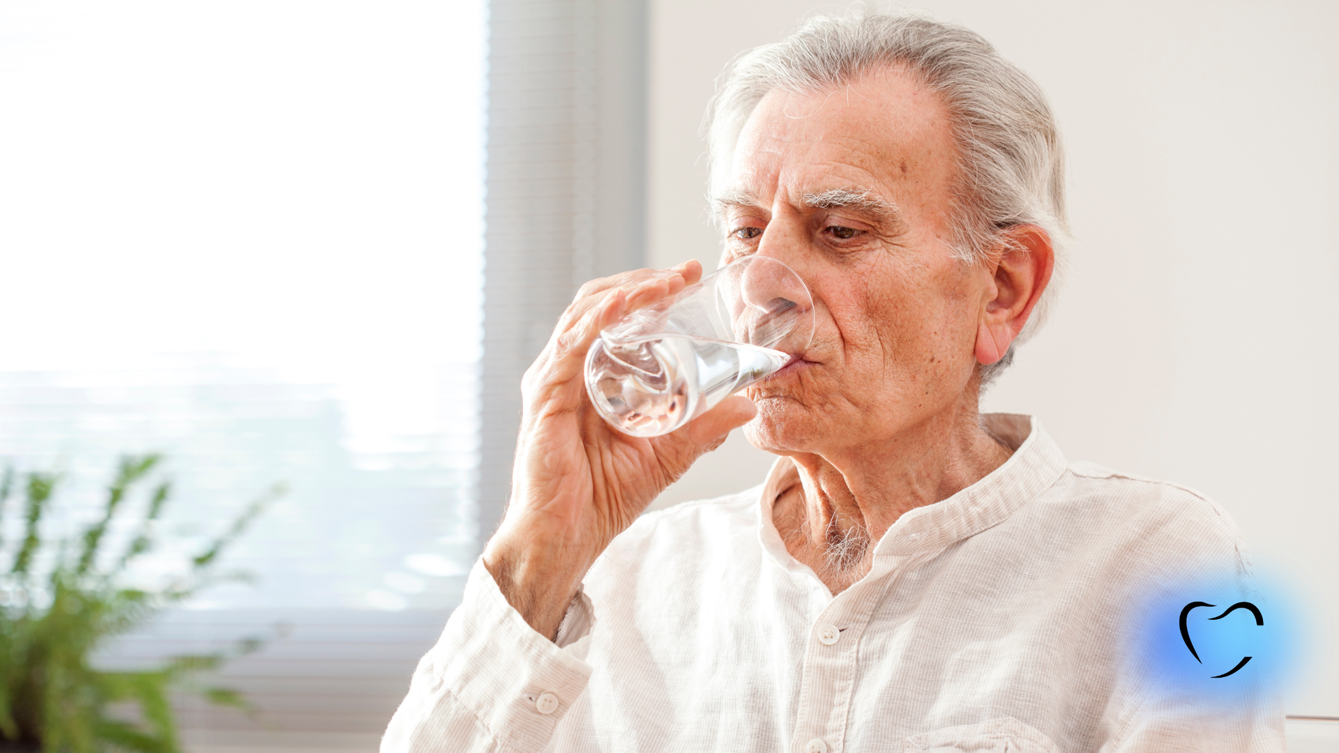 A person drinking from a glass of water in a brightly lit, indoor setting.
