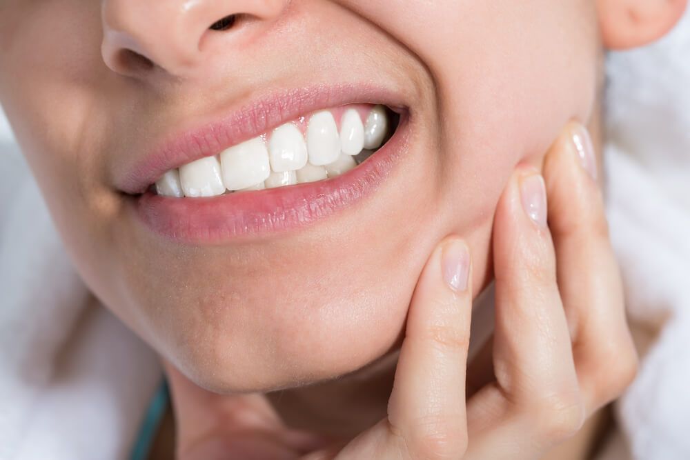 A woman is holding her mouth in pain because of a toothache.