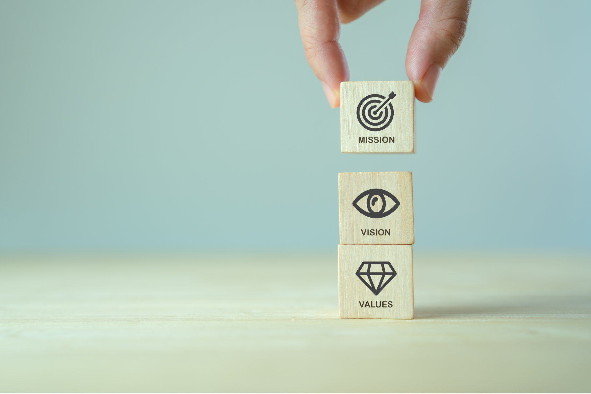 A person is holding a wooden block with a target , eye , and diamond on it.