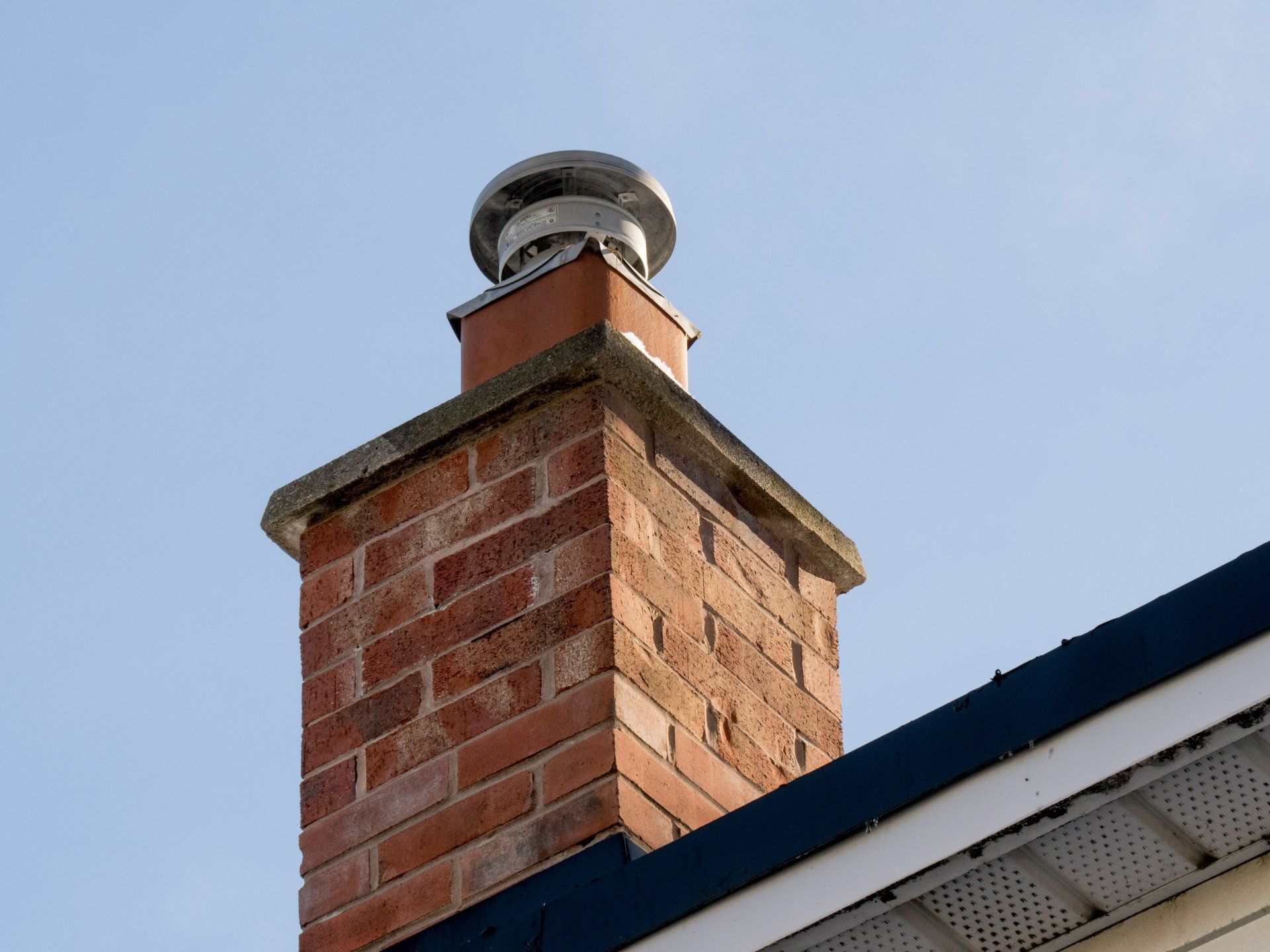 Une cheminée en briques au sommet d'une maison avec un toit bleu.