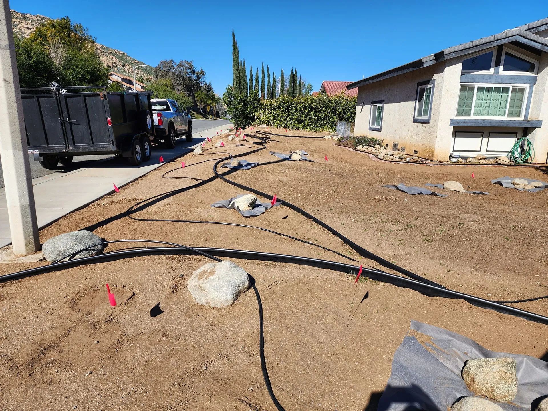 A truck is parked in the dirt in front of a house.