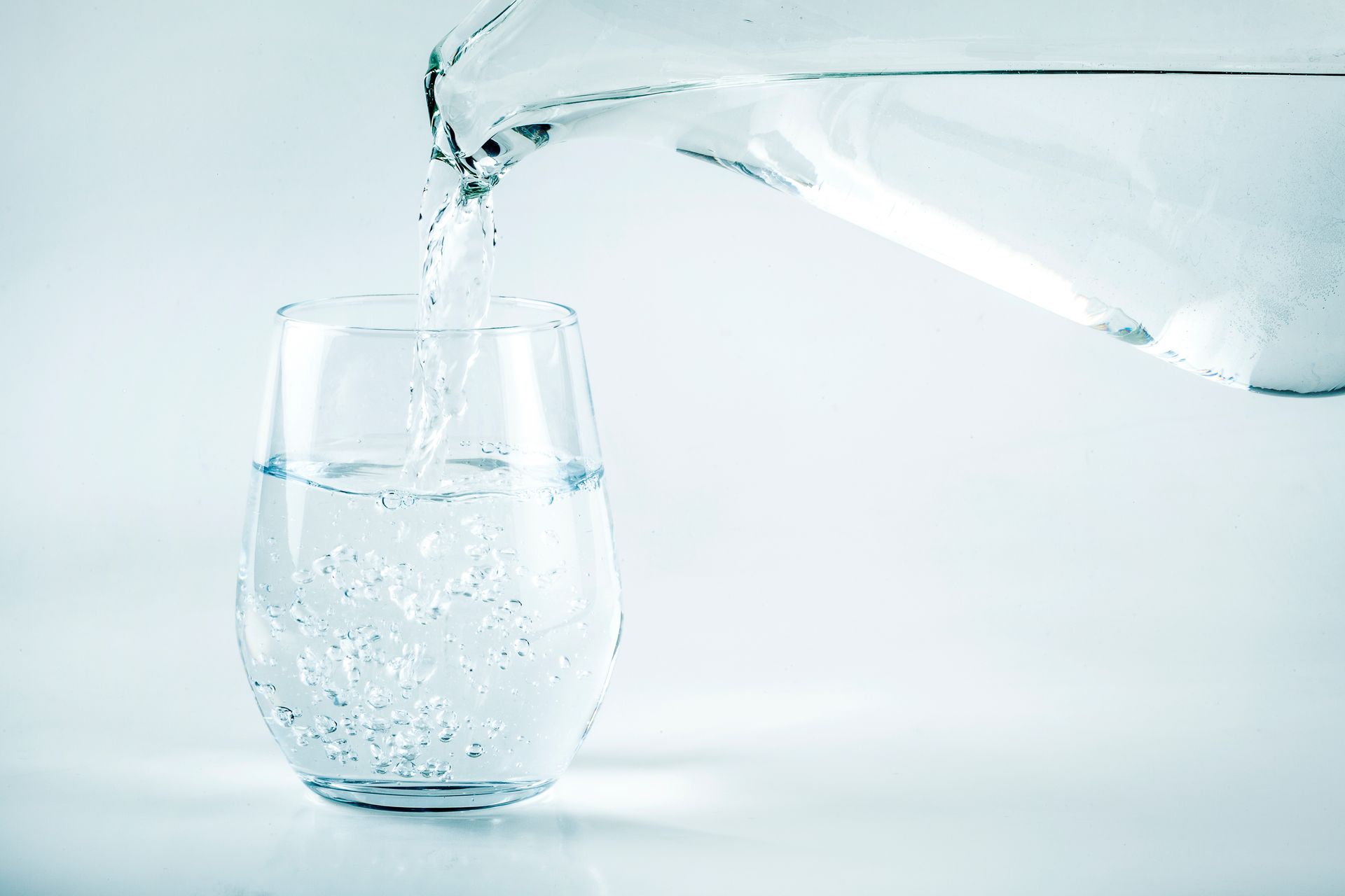 Water is being poured into a glass on a table.