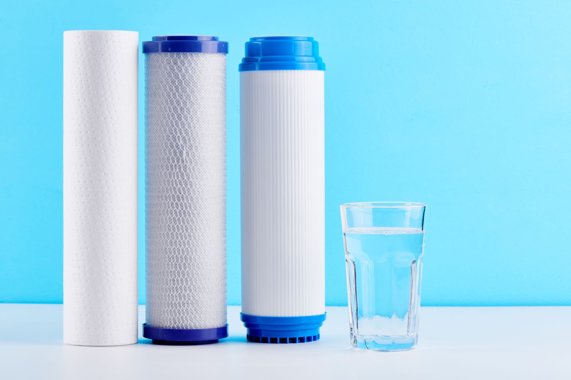Three water filters and a glass of water on a table.