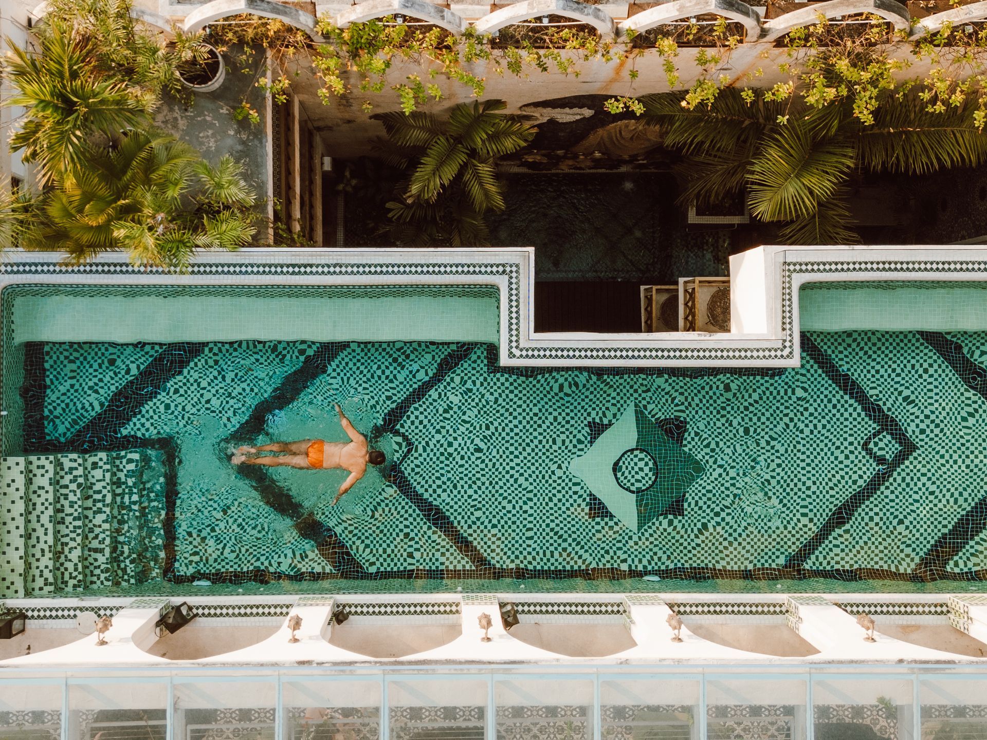An aerial view of a man floating on his back in a swimming pool.