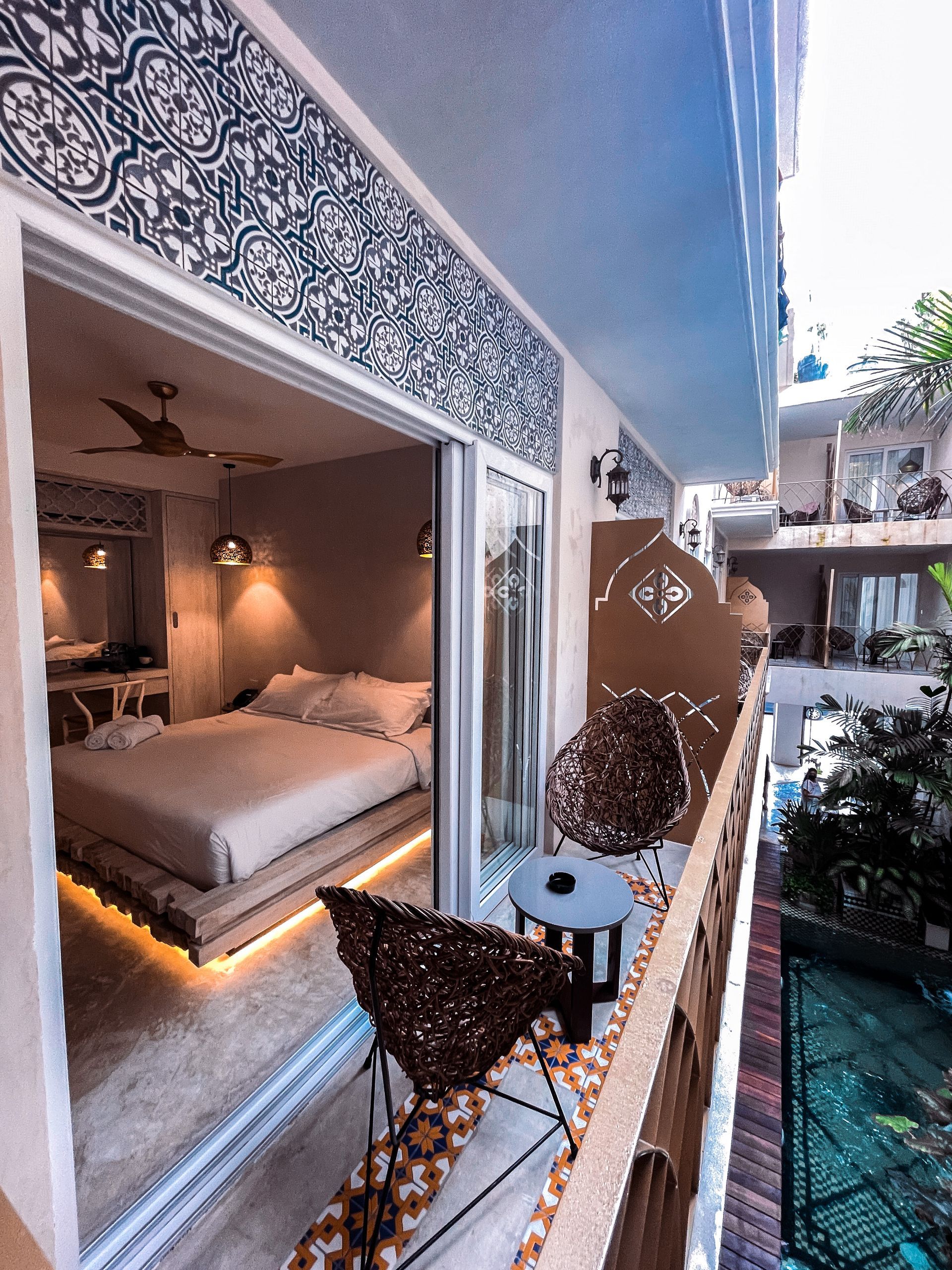 A balcony overlooking a bedroom with a bed and chairs