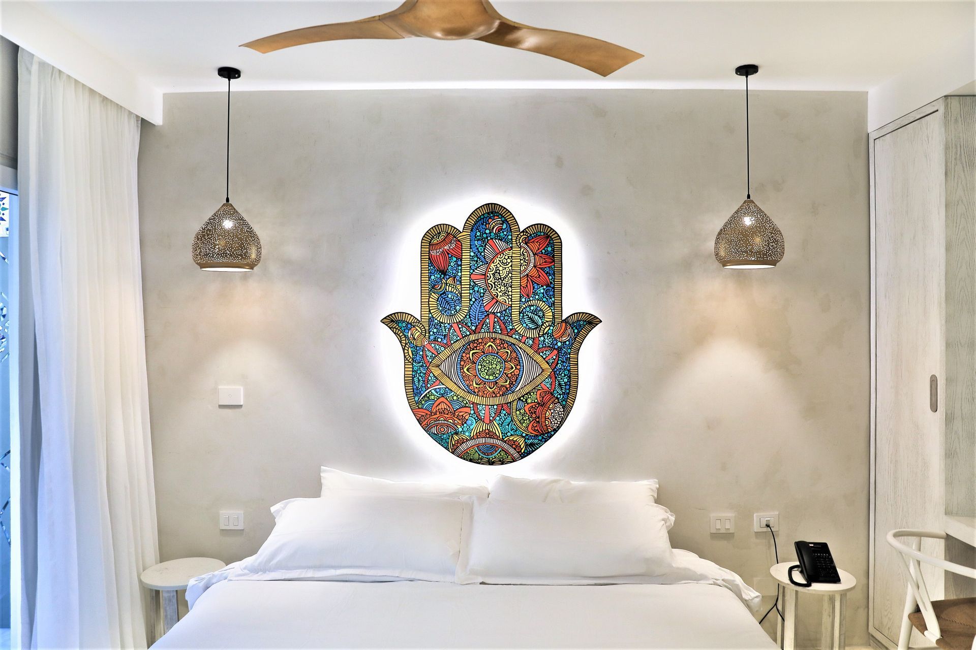 Un dormitorio con una mano de hamsa en la pared sobre la cama.