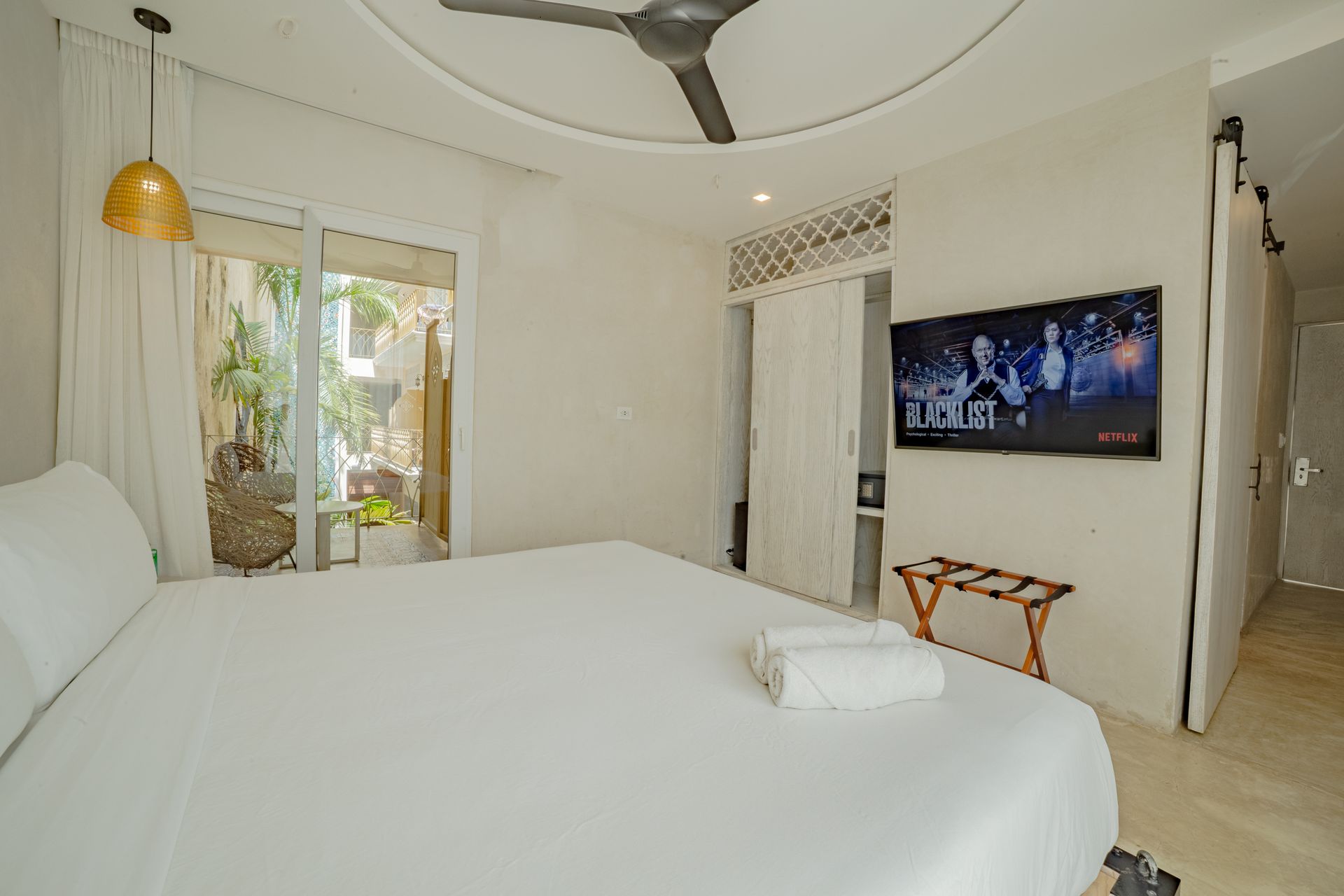 Bedroom with a white bed, TV, open doorway to a patio.