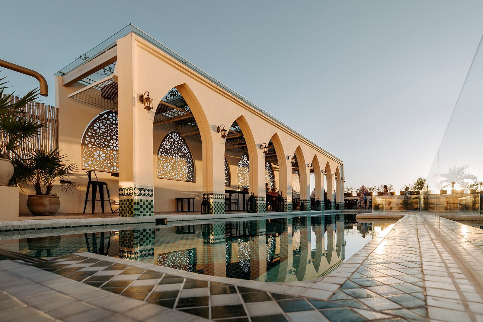 A large building with arches and a swimming pool in front of it.