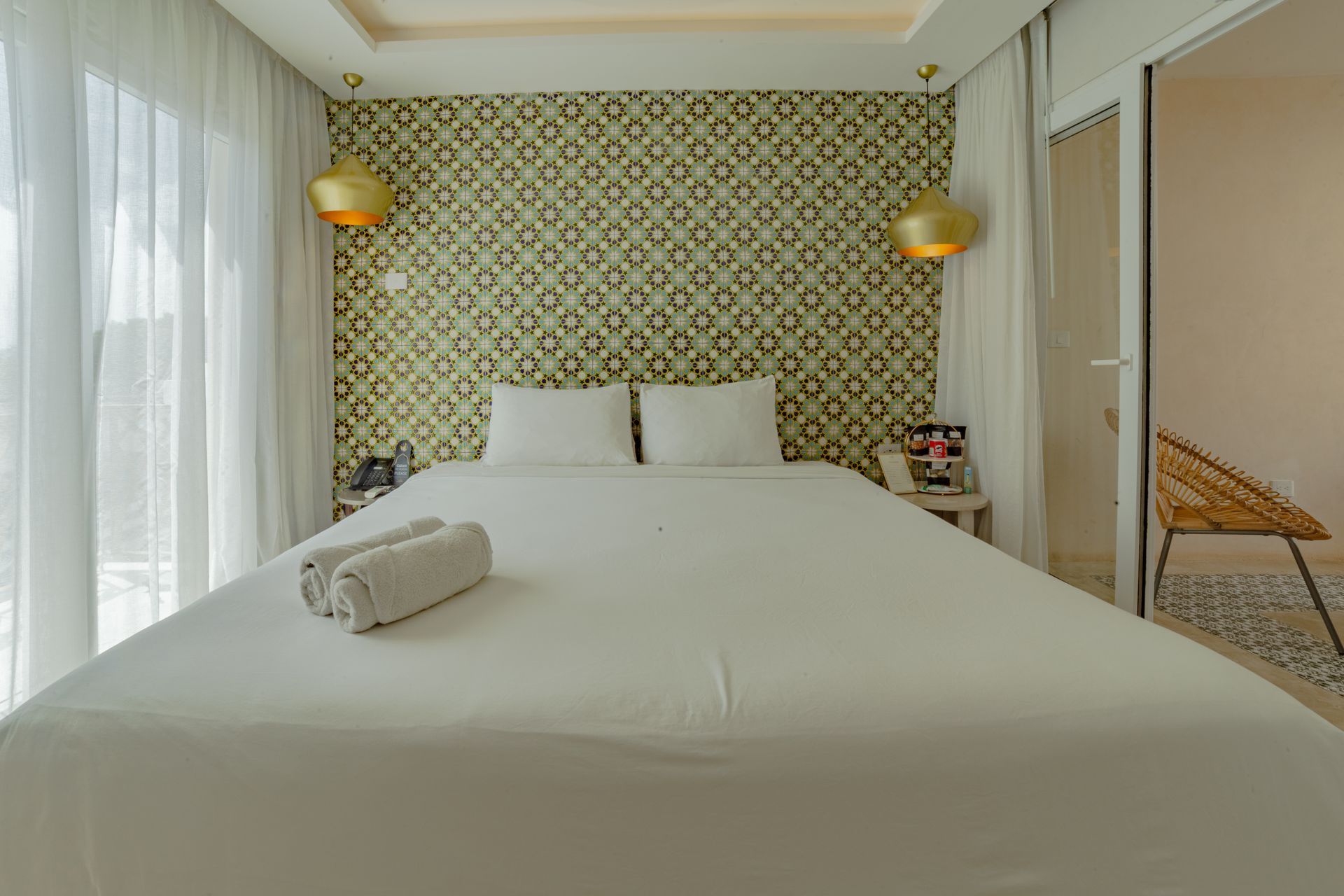 Bedroom with bed, patterned wallpaper, gold accents, and open doorway.