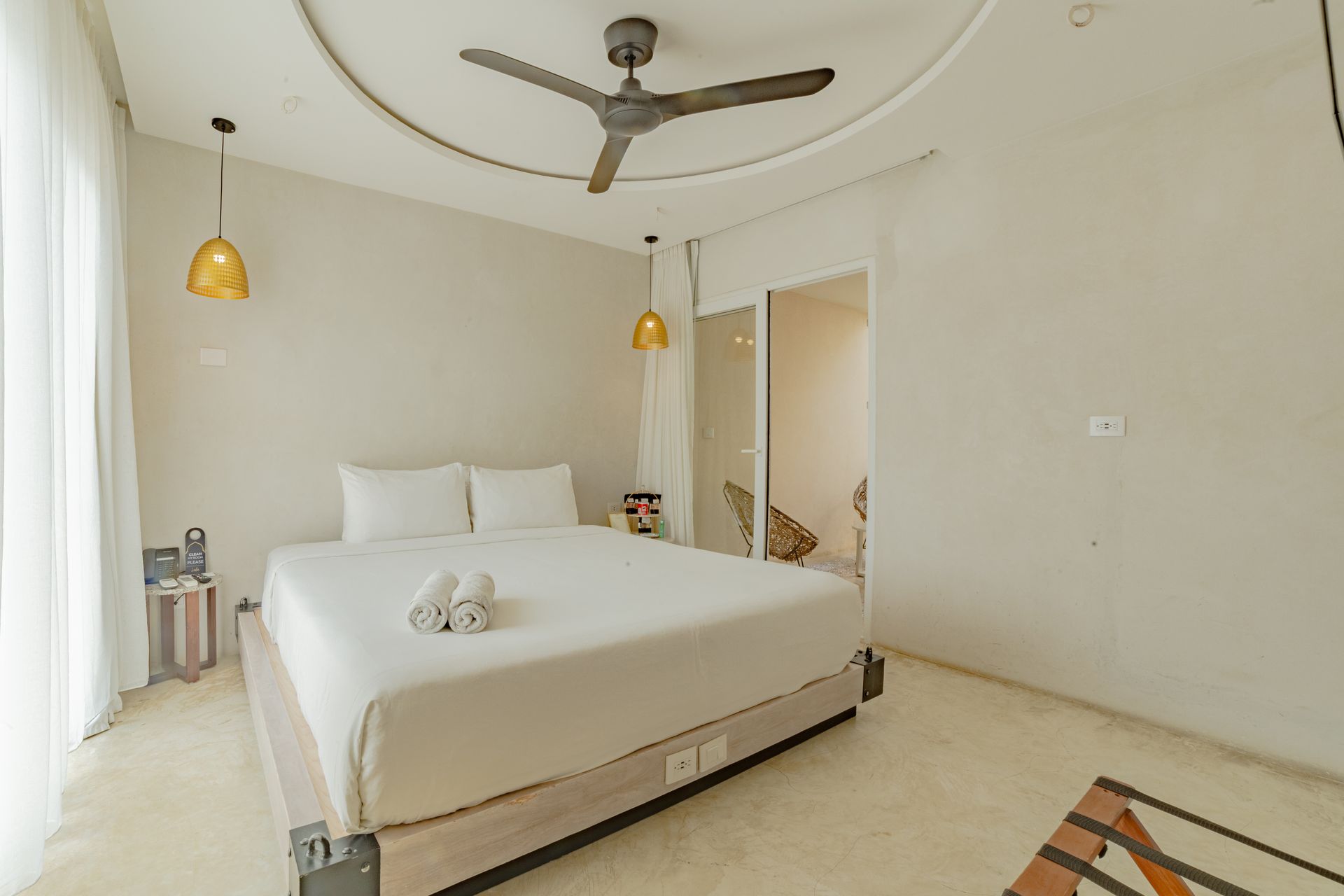 Bedroom with white bedding, overhead fan, gold pendant lights, and a patterned rug.