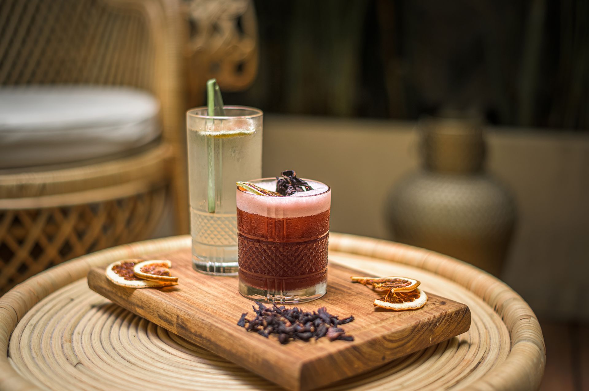 Two drinks are sitting on a wooden cutting board on a table.