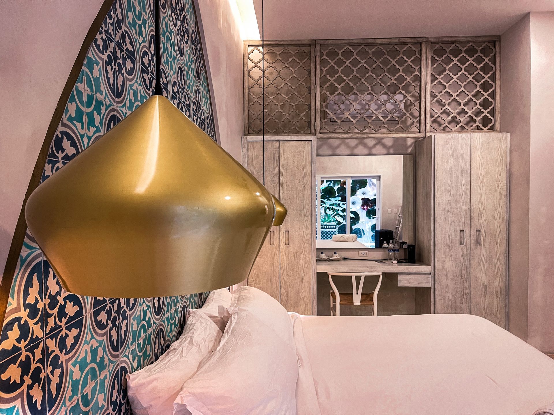 A bedroom with a bed , a desk , and a lamp hanging from the ceiling.