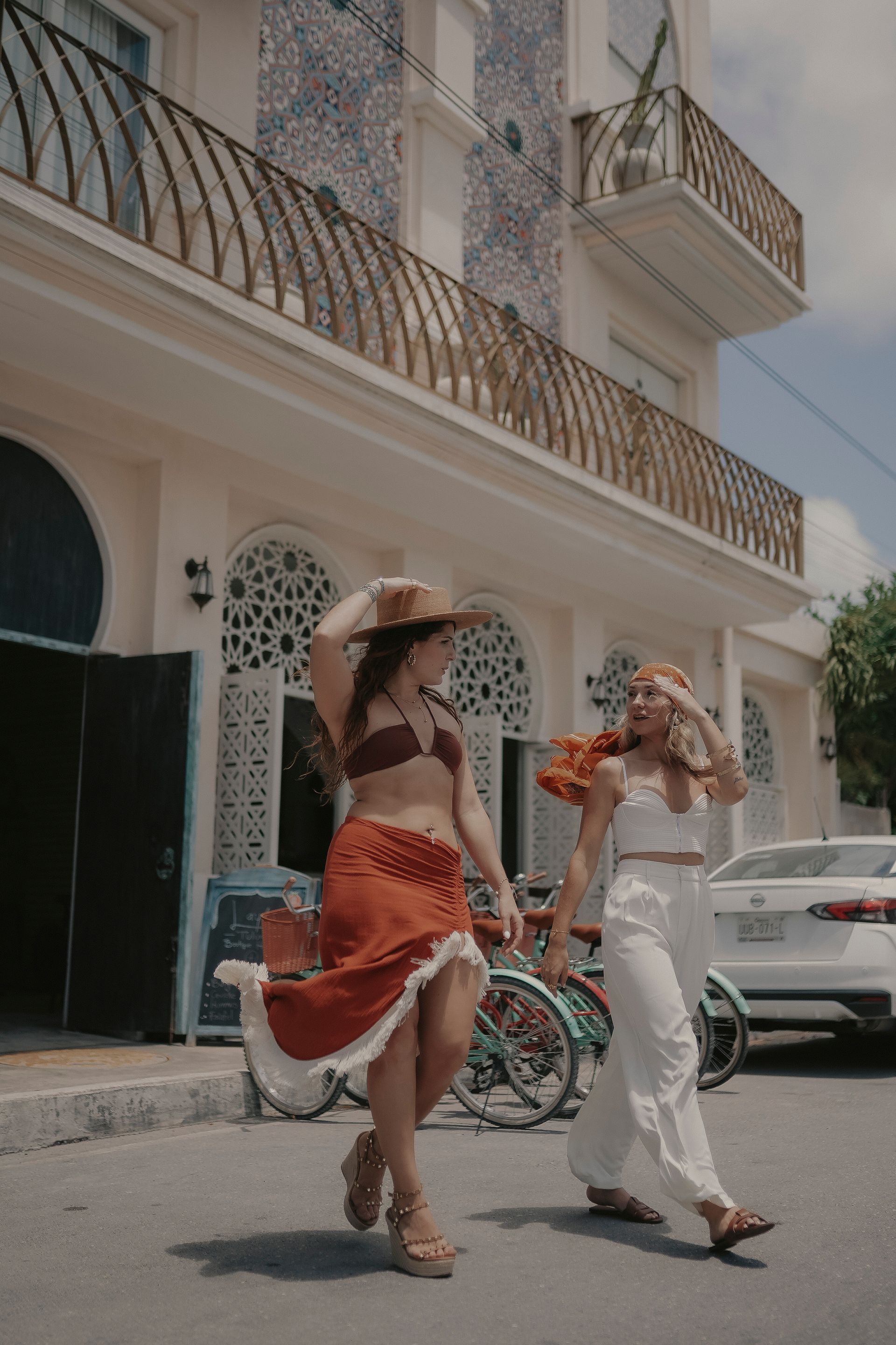 Two women are walking down the street in front of a building.