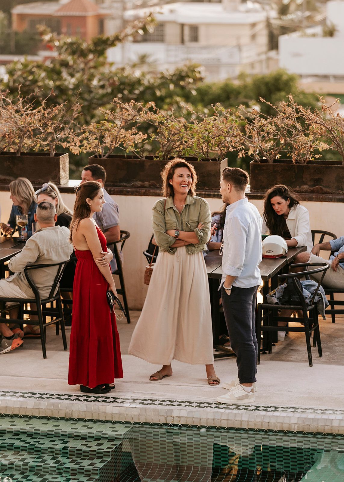 A group of people are standing around a pool talking to each other.