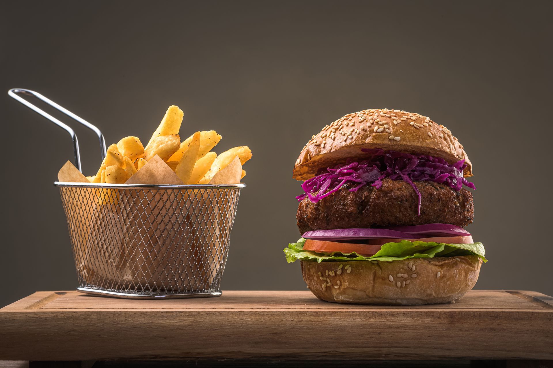 A hamburger and french fries are on a wooden cutting board.