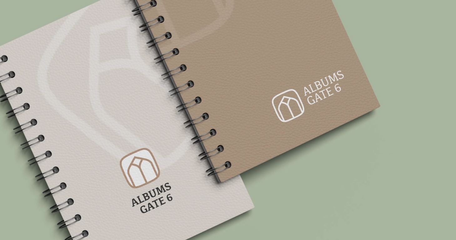 Two spiral notebooks, one cream and one tan, with a minimalist logo on a pale green background
