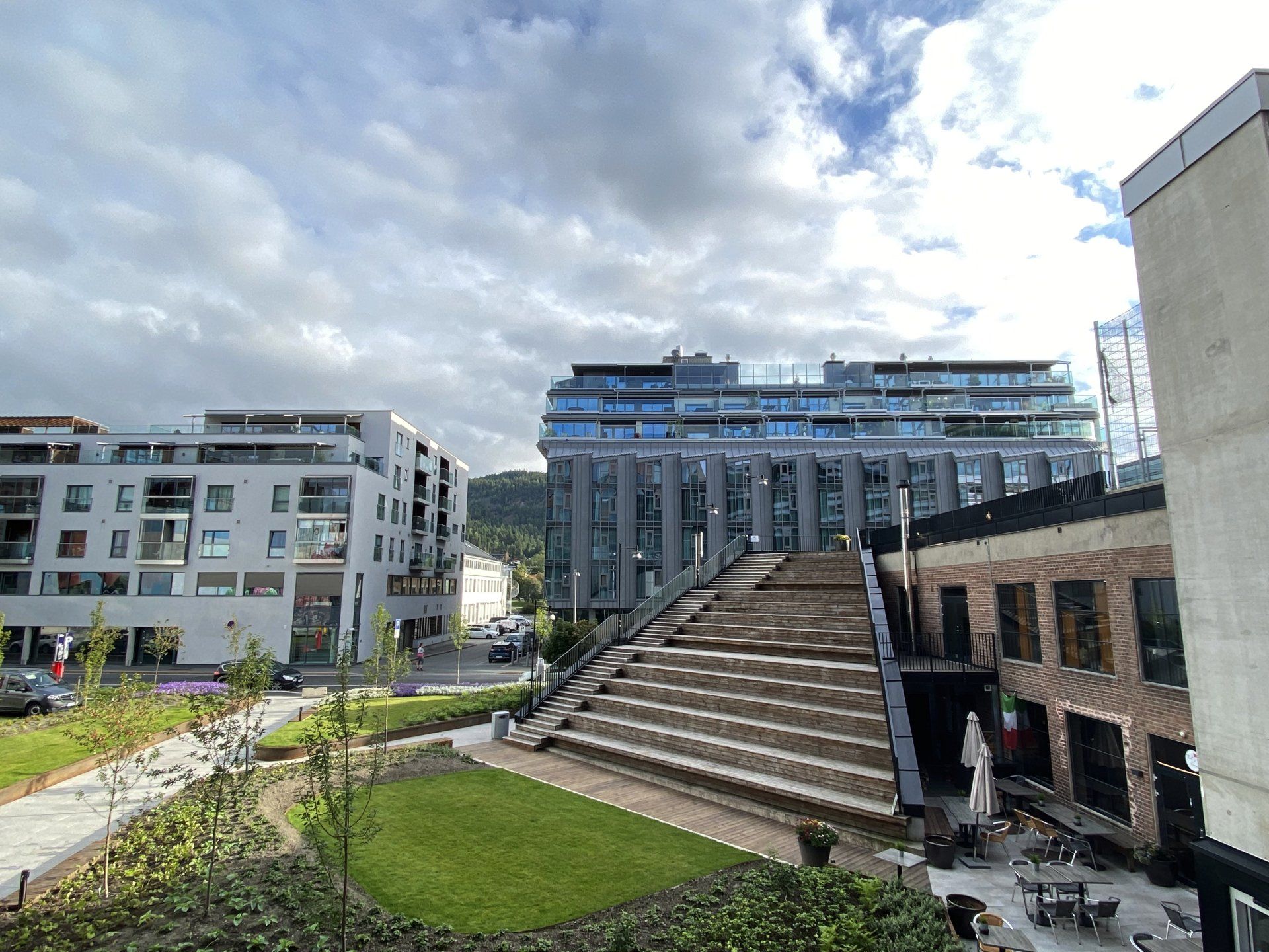 Moderne bygninger og etasjetrapper i urbane omgivelser under en overskyet himmel.