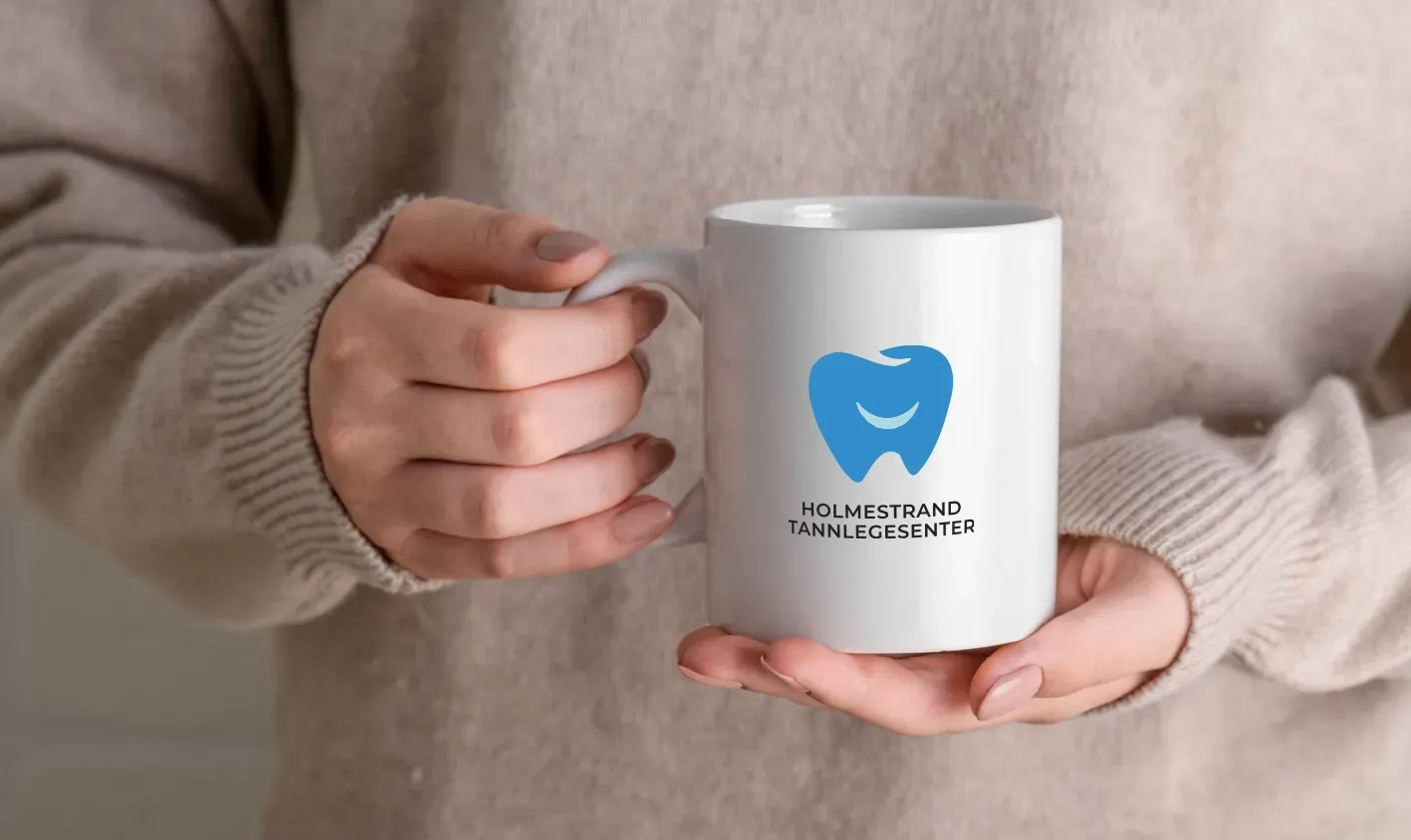 En person holder et kaffekrus med en tann på.