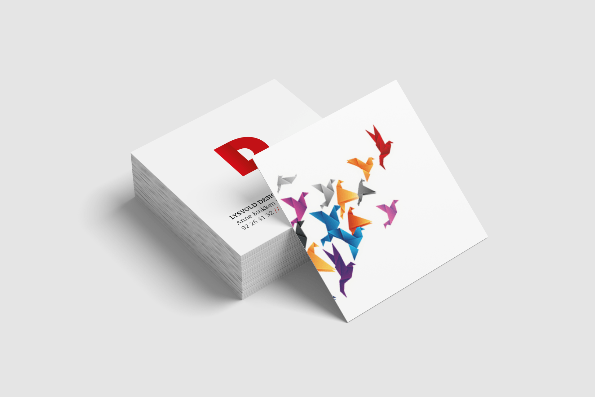 Stack of white square business cards, one showing colorful birds in flight.